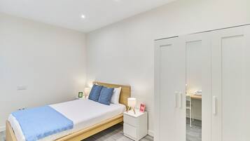 A bedroom with a bed, bedside table, lamp, and wardrobe.