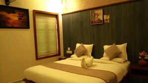 A hotel room with a large bed, a nightstand, a vase with flowers, and a painting on the wall. - Tatvaura Resort Wayanad (Vythiri)