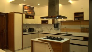 A modern kitchen with a central island, built-in microwave, and a large stove. - Tatvaura Resort Wayanad (Vythiri)