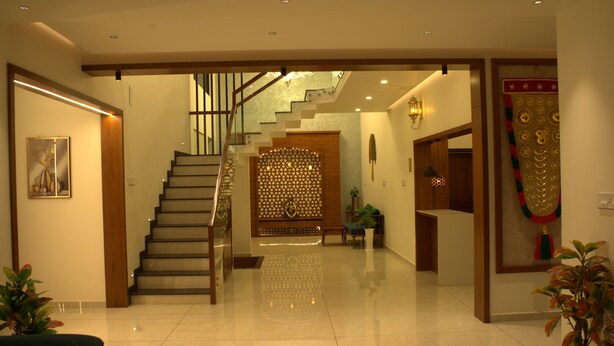 A spacious interior with a staircase leading to an upper level, a decorative wall, and a reception area. - Tatvaura Resort Wayanad (Vythiri)