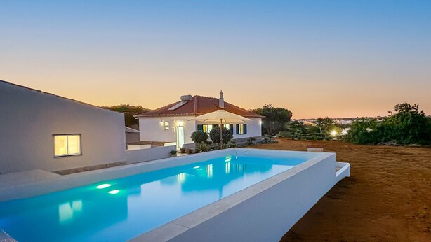 A modern house with a swimming pool, surrounded by a landscaped garden and a clear view of the sunset. - Casa do Monte by Check-in Portugal (Albufeira)