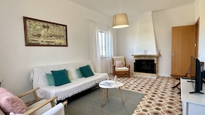 A living room with a sofa, armchair, fireplace, and a framed map on the wall. - Casa do Monte by Check-in Portugal (Albufeira)