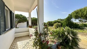 A covered outdoor area with a tiled floor, potted plants, and a view of trees and a distant landscape. - Casa do Monte by Check-in Portugal (Albufeira)