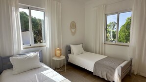 A bedroom with two beds, a small table with a lamp, and a wall-mounted dreamcatcher. - Casa do Monte by Check-in Portugal (Albufeira)