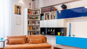 A living room with a sofa, bookshelves, and a blue accent wall. - GuestHost - Venezia Nuova Apartment Livorno (Livorno)