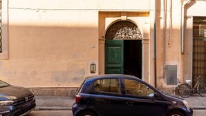 A building with a green door, a bicycle parked outside, and a car parked in front. - GuestHost - Venezia Nuova Apartment Livorno (Livorno)