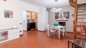 A modern kitchen with white cabinets, a dining area with a white table and chairs, and a staircase. - GuestHost - Venezia Nuova Apartment Livorno (Livorno)