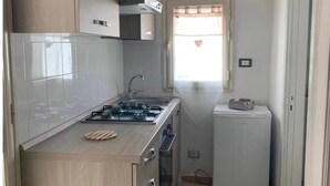 Una cocina compacta con estufa a gas, horno empotrado, microondas y refrigerador.