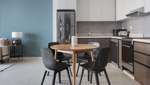 A modern kitchen with a built-in refrigerator, microwave, and oven. There is a dining area with a round table and four chairs.
