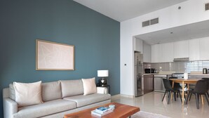 A modern living room with a sofa, coffee table, and a painting on the wall.
