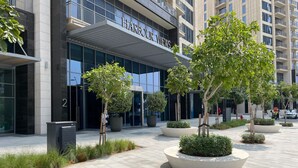A modern building with the sign "HARBOUR VIEWS" and a landscaped courtyard with trees and planters.