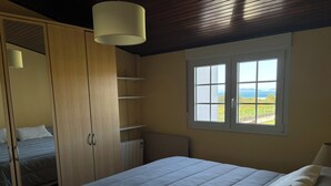 Un dormitorio con cama, armario, radiador y ventana con vistas al exterior.