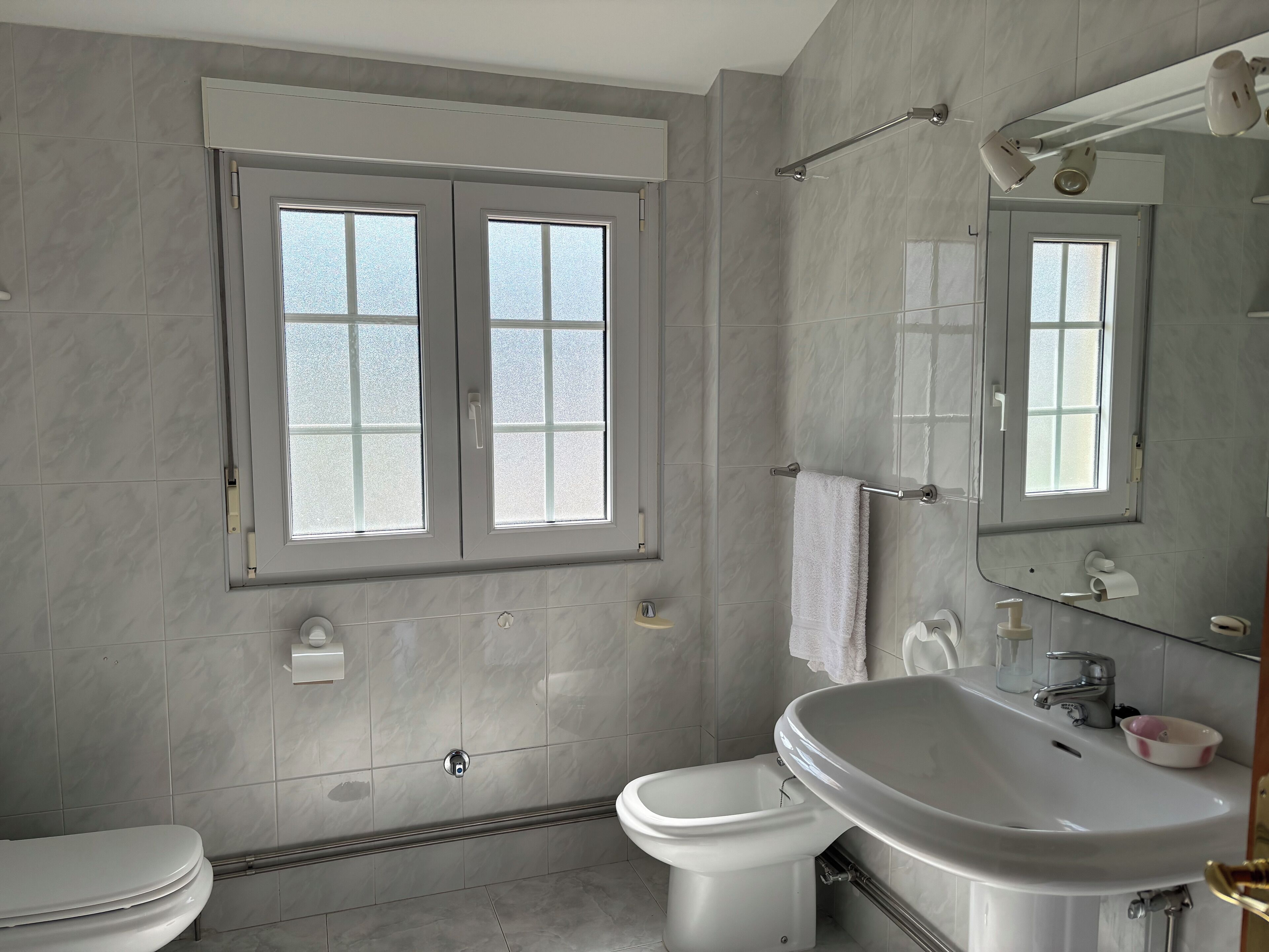 A modern bathroom with a toilet, bidet, and sink.