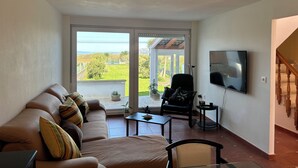 Una sala de estar con un sofá, un televisor, una silla y una mesa.
