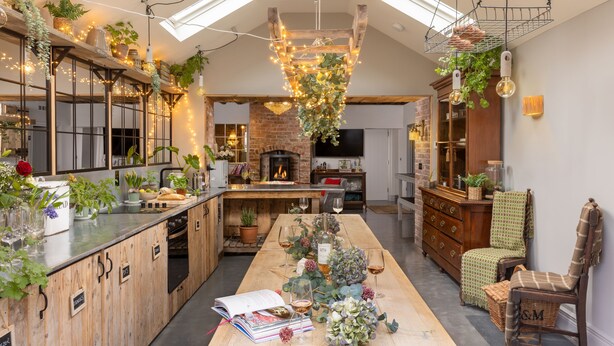 A modern kitchen with a central island, wooden cabinetry, and a brick fireplace. - Boutique, three storey Georgian Town House, ground floor apartment with garden (Nantwich)