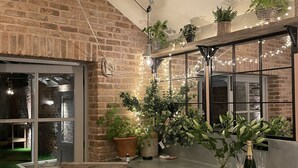 A kitchen with brick walls, wooden cabinets, and a window overlooking a garden. There are potted plants on the counter and a chalkboard. - Boutique, three storey Georgian Town House, ground floor apartment with garden (Nantwich)