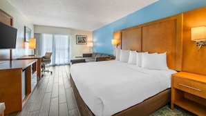 A hotel room with a large bed, a desk, a chair, a TV, and a window with curtains. - Unwind in a Peaceful Haven w/Balcony | Minutes from Speedway Action (Daytona Beach)