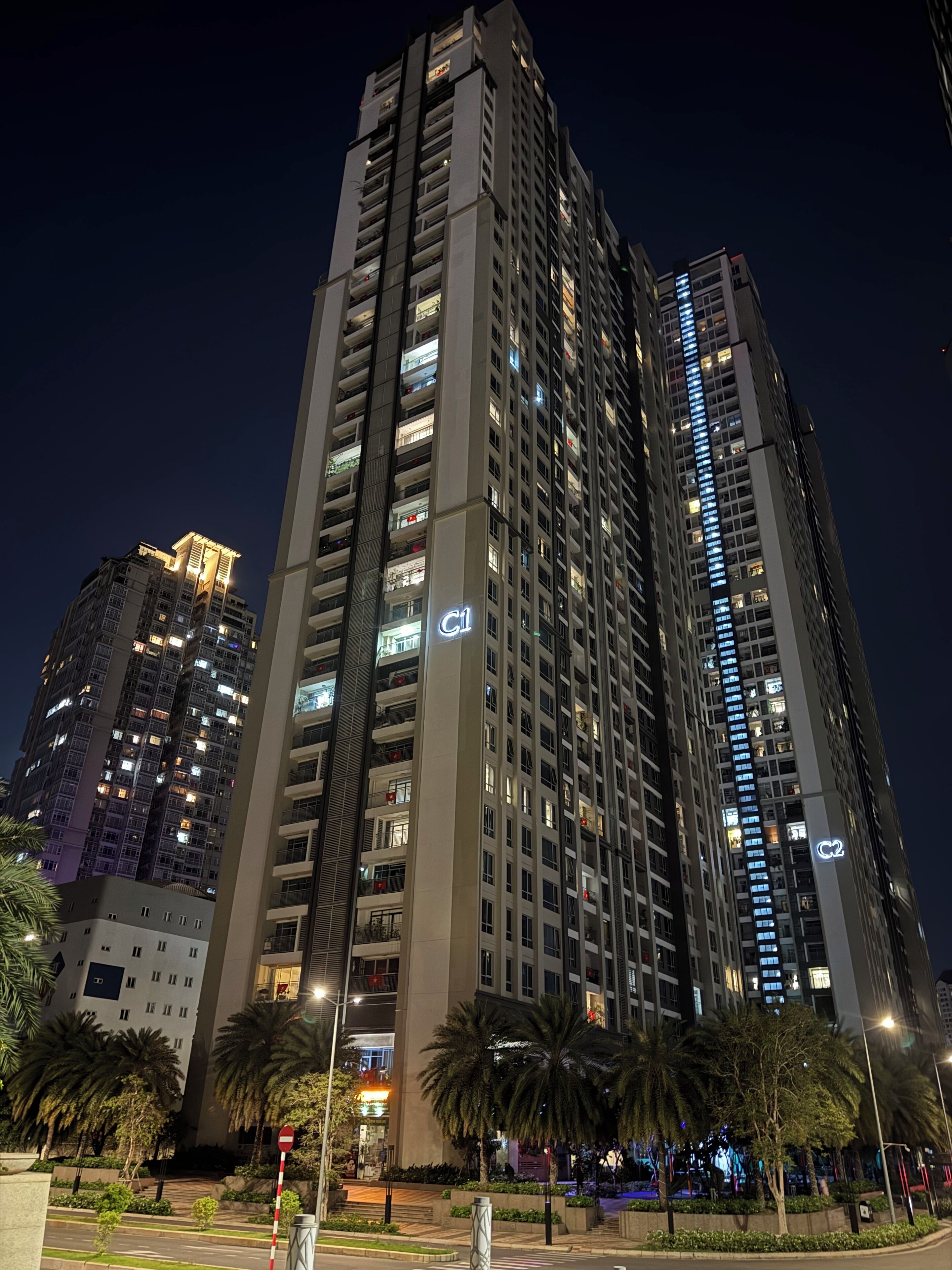 A high-rise building with multiple floors, illuminated windows, and balconies.