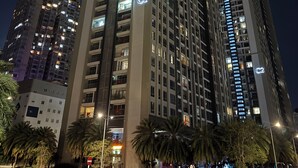 A high-rise building with multiple floors, illuminated windows, and balconies.