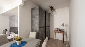 A modern living room with a dining area, a sofa, a coffee table with a plant, and a desk with a lamp and books. - Real Umberto I - Suite 1 by Wonderful Italy (Palermo)