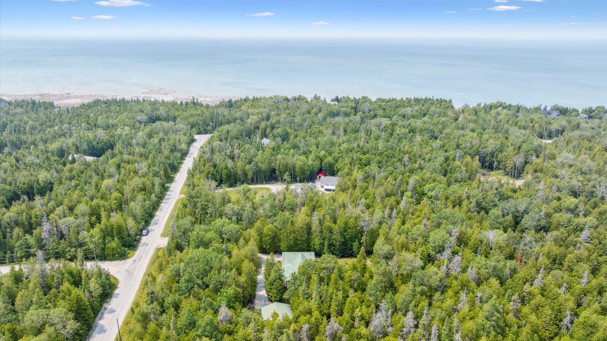 An aerial view of a forested area with a road and several buildings, likely a resort or lodge.