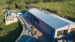 A modern building with a flat roof, a swimming pool, and a stone pathway leading to the entrance. - Kera Koxare Luxury Villa, Private Pool and Panoramic Mountain Views (Koxare Agiou Vasileiou)