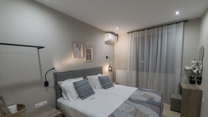 A modern bedroom with a bed, bedside table, lamp, air conditioning unit, and a mirror. - Kera Koxare Luxury Villa, Private Pool and Panoramic Mountain Views (Koxare Agiou Vasileiou)