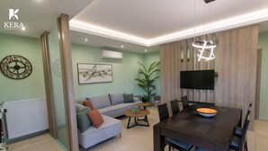 A modern living room with a sofa, coffee table, and dining table. There is a TV mounted on the wall and a plant in the corner. - Kera Koxare Luxury Villa, Private Pool and Panoramic Mountain Views (Koxare Agiou Vasileiou)