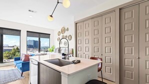 A modern kitchen with a central island, large windows, and a city view. - Skyline View Serene Oasis (Atlanta)