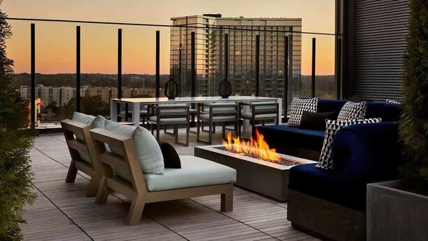 A rooftop terrace with outdoor seating, a fire pit, and a city view at sunset. - Skyline View Serene Oasis (Atlanta)