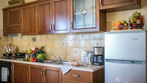 Une cuisine avec des armoires en bois, un évier en acier inoxydable, une cuisinière et un réfrigérateur.