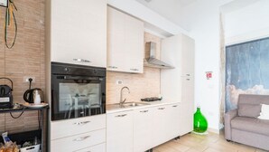Et moderne køkken med indbygget ovn, vask og komfur. En grøn flaske ligger på gulvet.