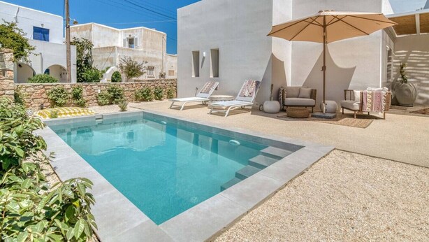 A modern pool area with a clear pool, lounge chairs, and a large umbrella. - Villa Alma - Aliki Center (Aliki)