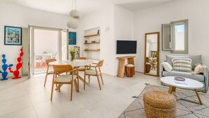 A modern living room with a dining area, a sofa, a TV, and a large window. - Villa Alma - Aliki Center (Aliki)
