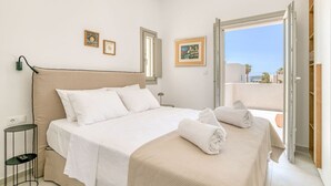 A bedroom with a bed, a bedside table, a lamp, and a view of the outside. - Villa Alma - Aliki Center (Aliki)