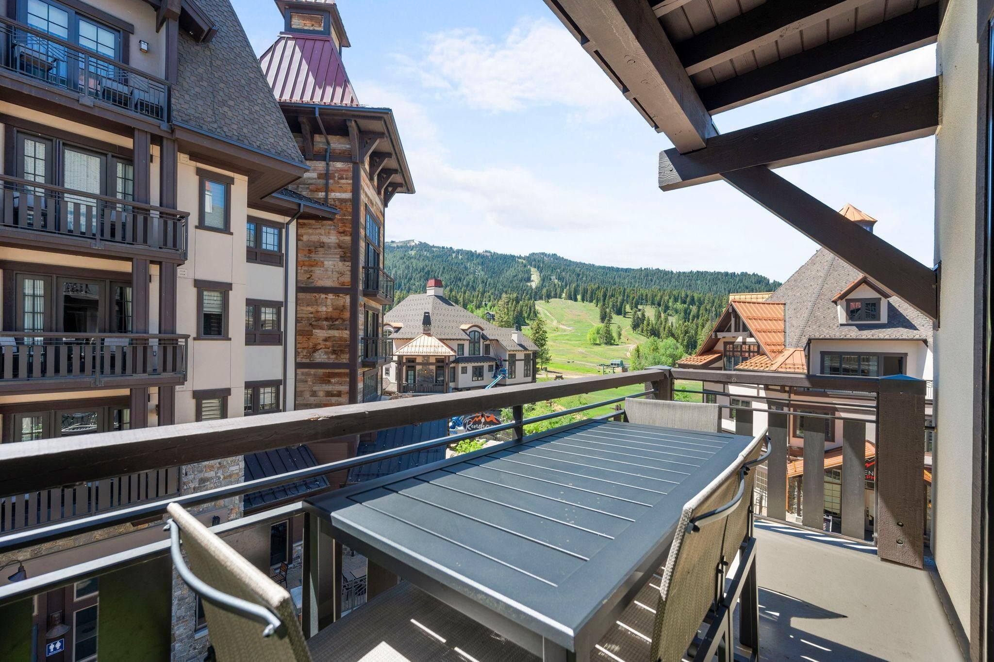 A multi-story building with balconies, a ski lift, and a view of a ski resort.