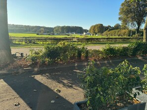 A view of a park with a paved path, greenery, and a distant field. - Longstay Achterhoek (Zeddam)