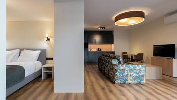Un espacio de estar moderno con una cama, un sofá, un televisor y una cocina.