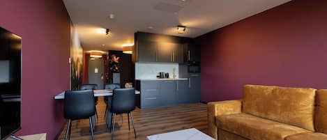 A modern living room with a sofa, dining area, and kitchen.