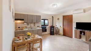 A compact kitchen with a dining area, a TV, and a small refrigerator. - Apartment 'Prima Luce' with Sea View, Private Terrace and Wi-Fi (Vico Equense)