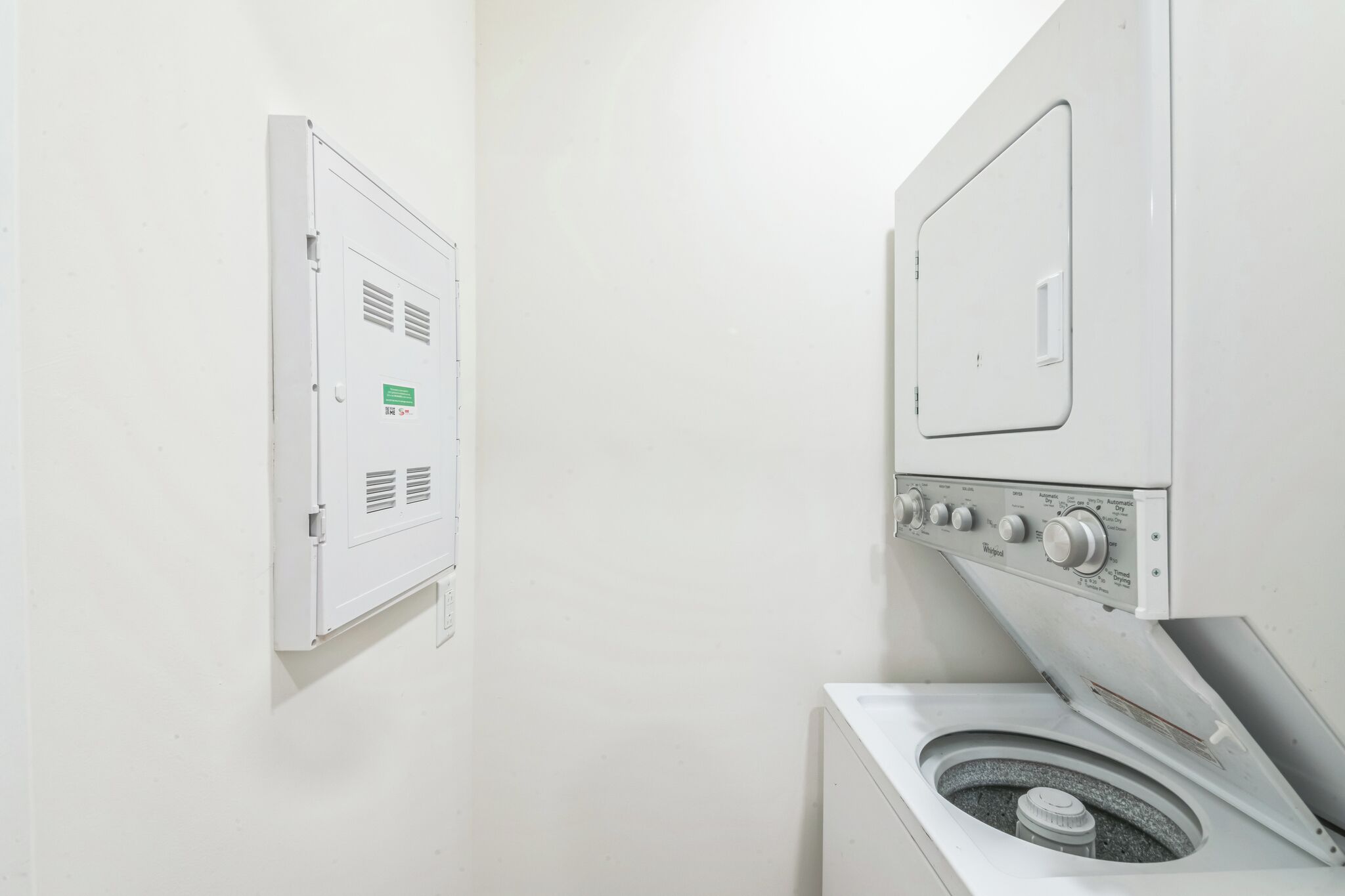 Un lavadero con lavadora y secadora, ambos blancos, y un contador de servicios en la pared.