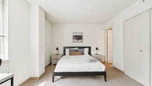 A bedroom with a bed, bedside tables, a nightstand, a wardrobe, and a painting on the wall. - Legacy at Imperial Village 417 I 2 Bed 2 Bath (Ric hmond)