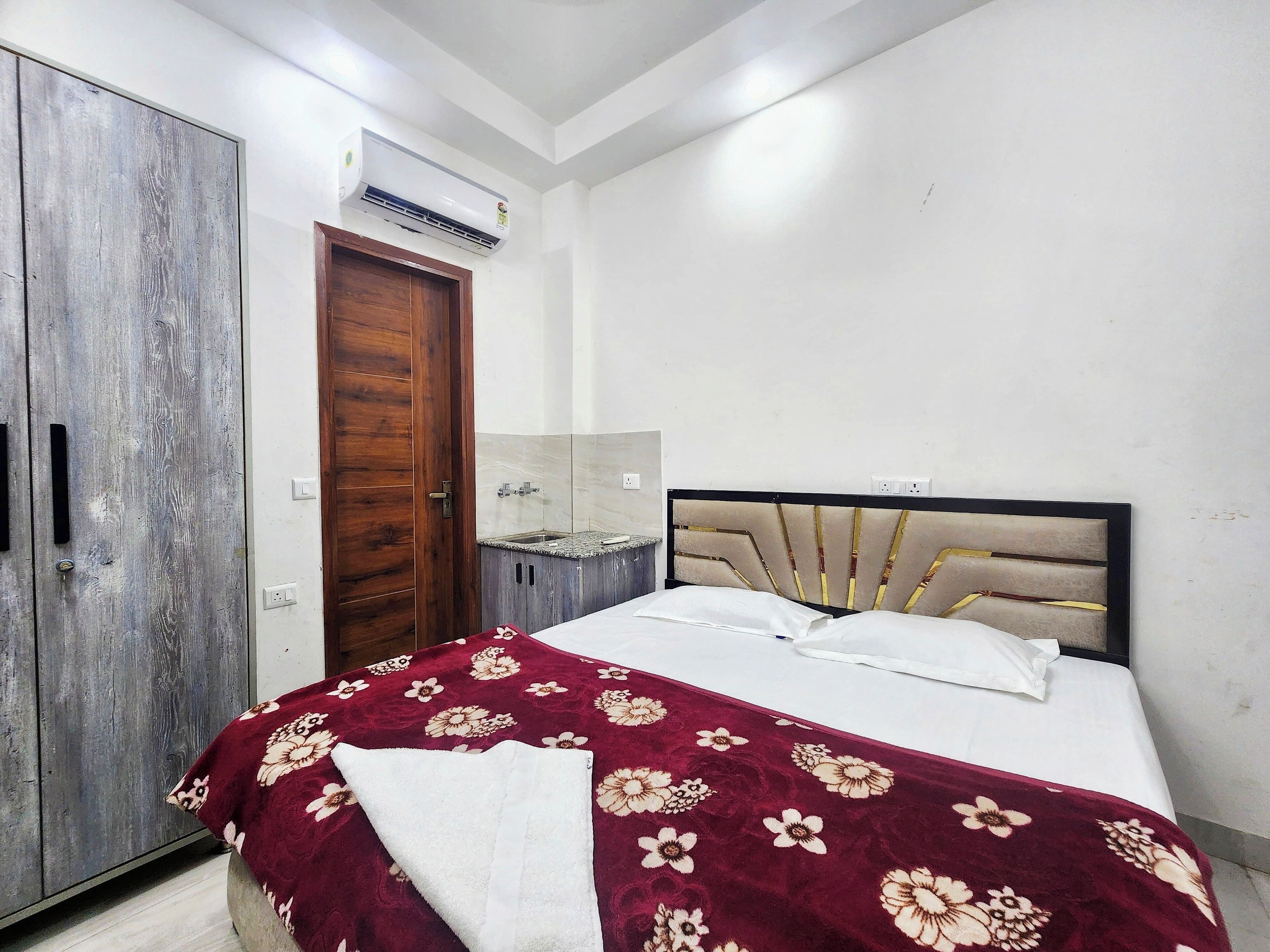 A bedroom with a bed, a wardrobe, a bathroom, and an air conditioning unit.