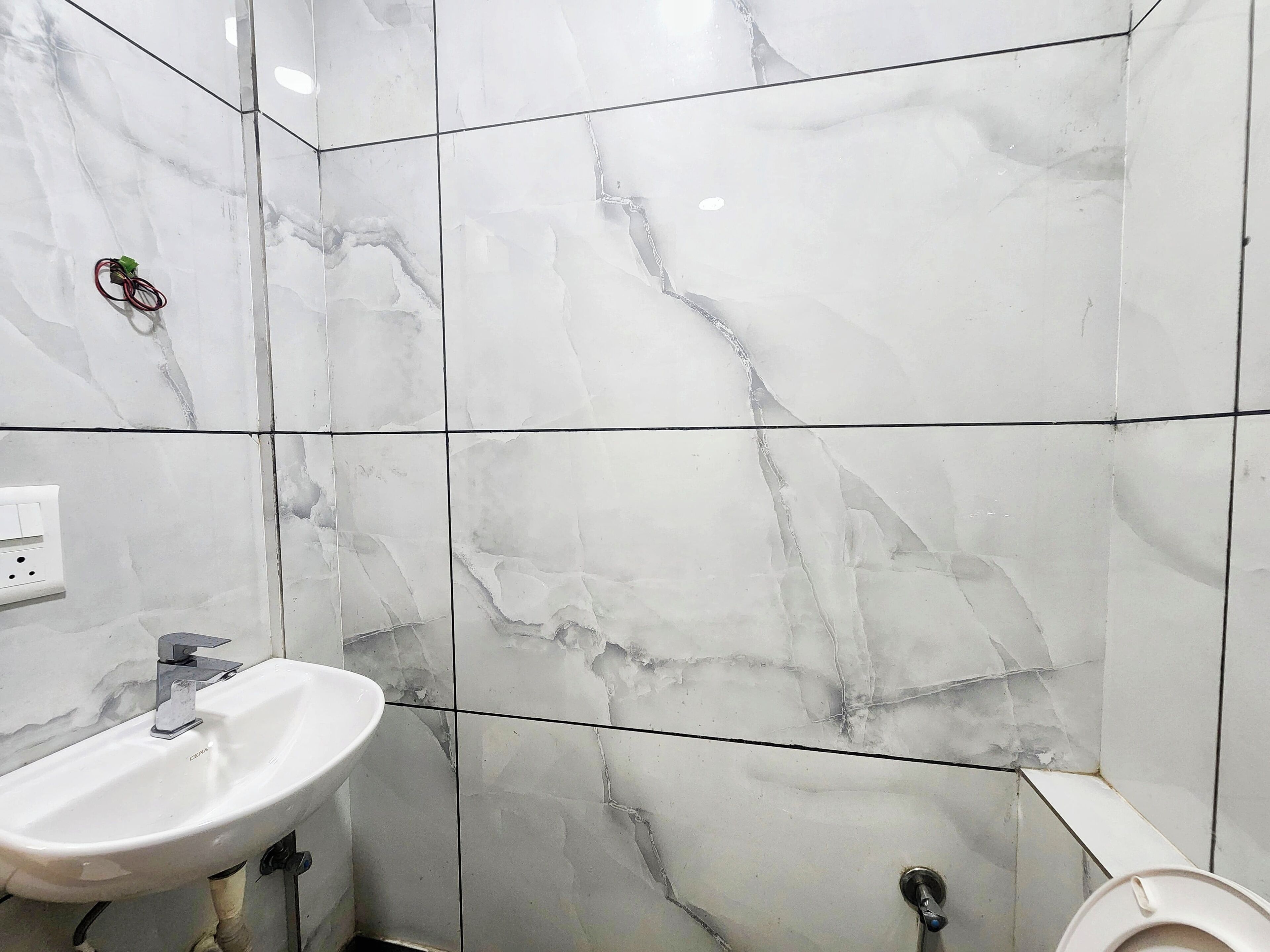 A bathroom with white marble tiles, a white sink, and a toilet.