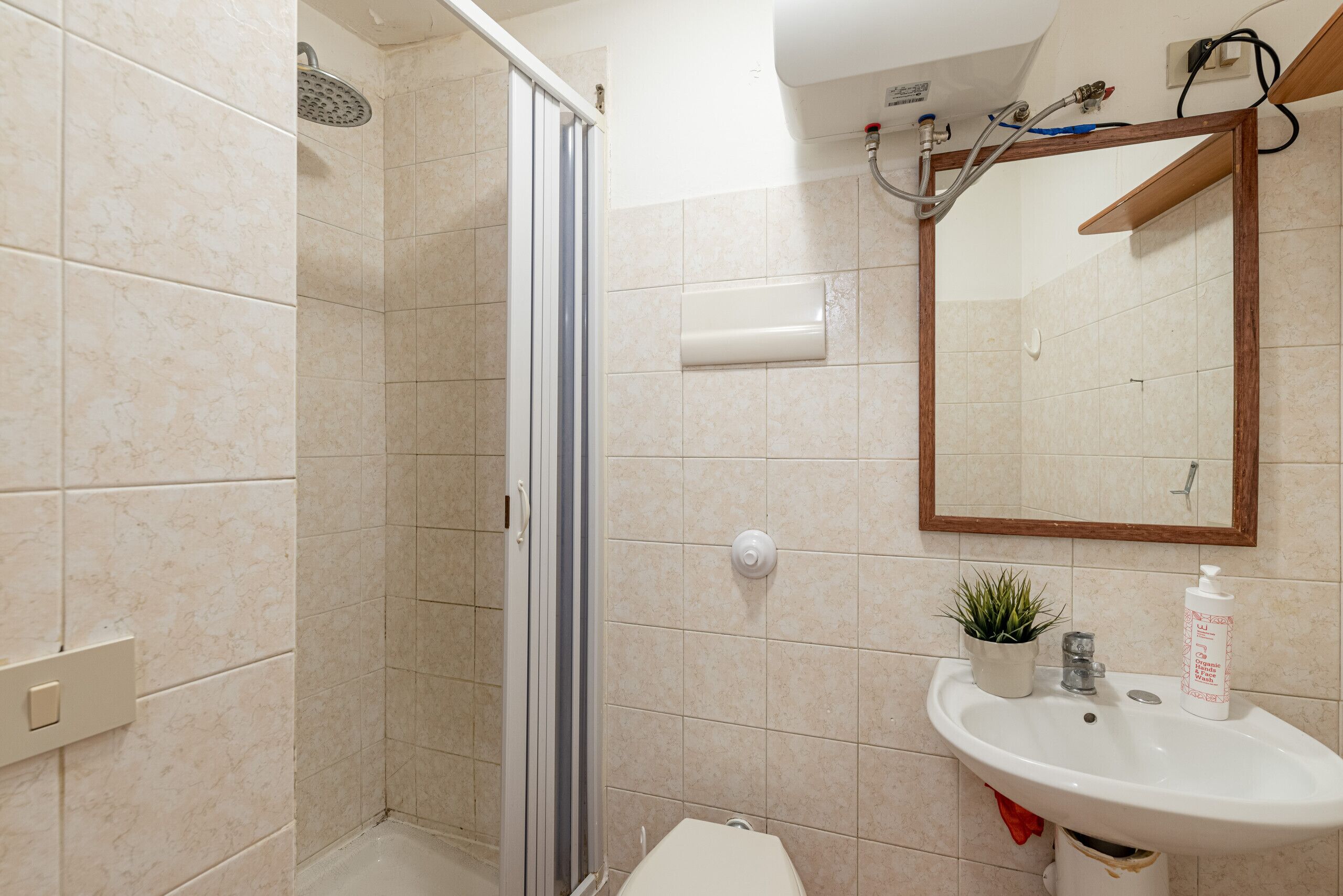 Un bagno con doccia, WC, lavandino e specchio.