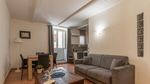 A living room with a grey sofa, a wooden coffee table, a dining area with a table and chairs, and a kitchen in the background. - Real Umberto I Suite 2 by Wonderful Italy (Palermo)