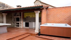 Eine Terrassenanlage mit Whirlpool, einer Steinsitzbank und einer Küche mit gelben Schränken.