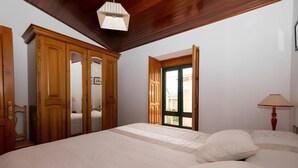 Ein Schlafzimmer mit einem großen Bett, einem Holzschrank und einem Fenster mit Blick.