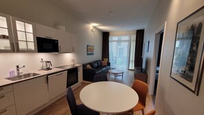 A modern kitchen with a dining area, a sofa, and a TV. - New apartment 5min to airport at Kokstad train station (Vestland)