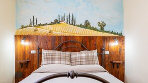 A bed with a wooden headboard, two bedside lamps, and a painting of a landscape on the wall.